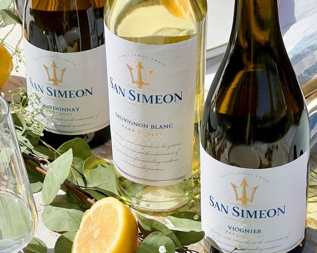 Bottles of San Simeon Paso Robles Viognier and Sauvignon Blanc with Monterey Chardonnay, fresh lemons and greenery.
